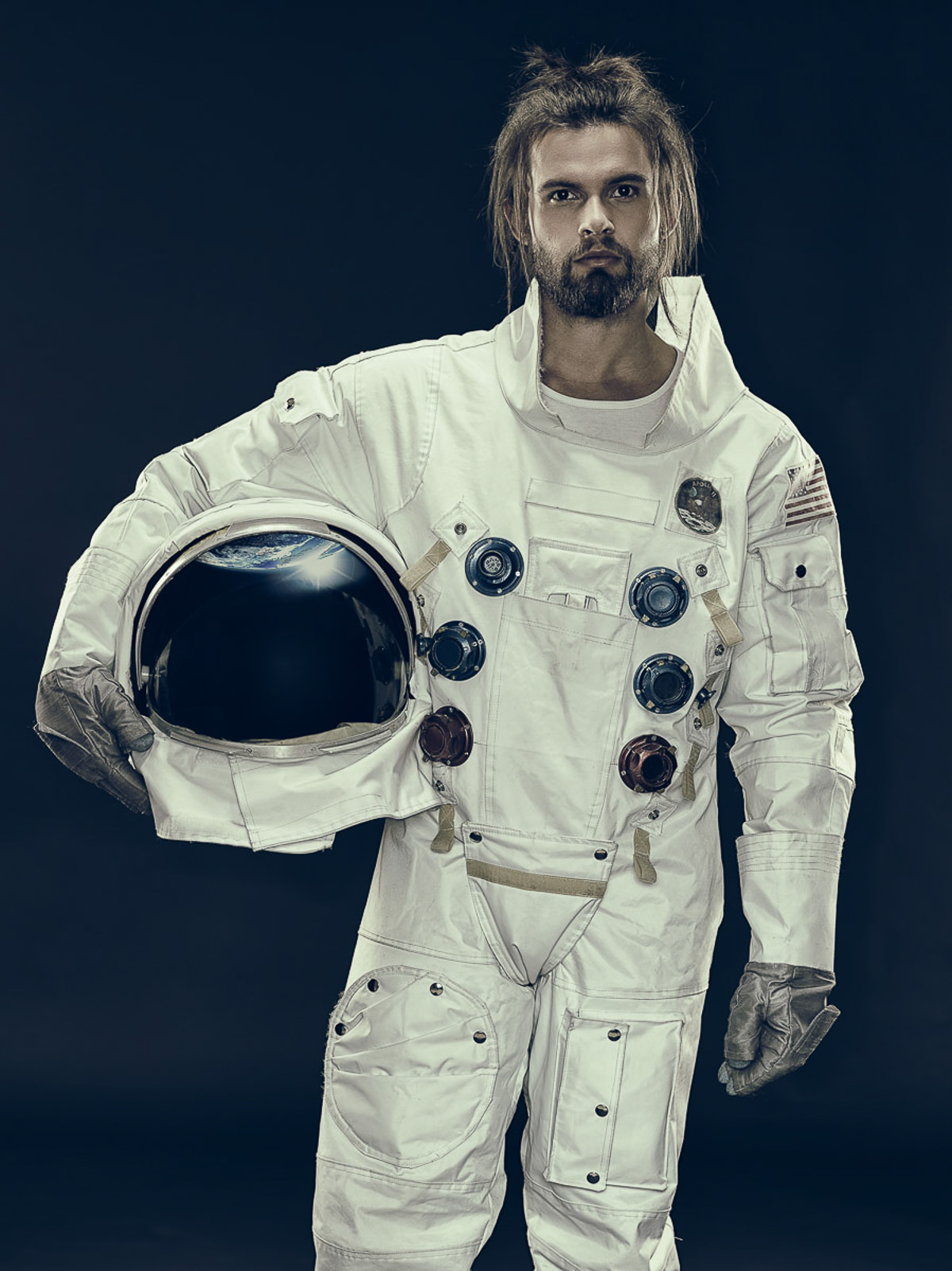 Porträt eines modernen Astronauten in einem weißen Raumanzug, der seinen Helm hält. Stilvolle Beleuchtung, dunkler Hintergrund.