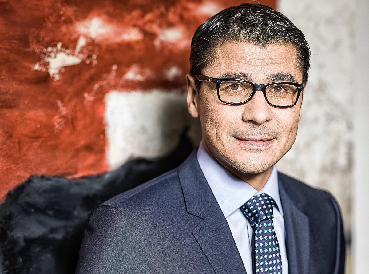 Ein Mann mit Brille und Anzug steht für ein Foto, strahlt Professionalität und Charisma aus.