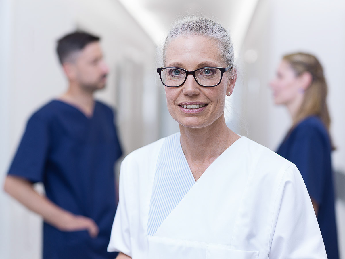 Eine Frau in Arbeitskleidung steht in einem Flur eines Medizinischen Versorgungszentrums (MVZ).