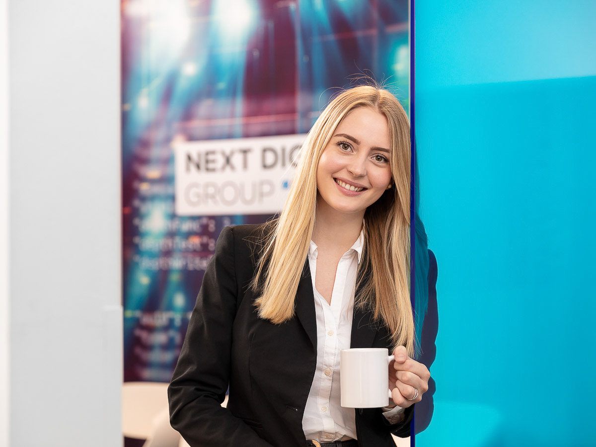 Eine Frau im Businessanzug hält eine Kaffeetasse und genießt eine kurze Pause.