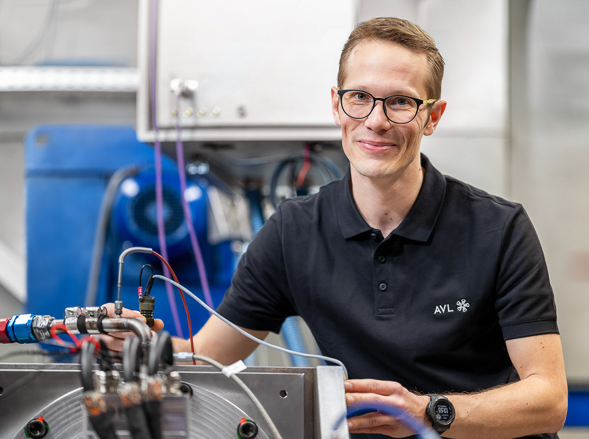 Ein Mann mit Brille arbeitet an einer Maschine in einer industriellen Umgebung.