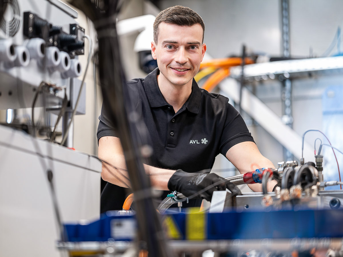 Ein Mann in einem schwarzen Shirt ist mit einer Maschine beschäftigt und zeigt Konzentration bei der Arbeit.