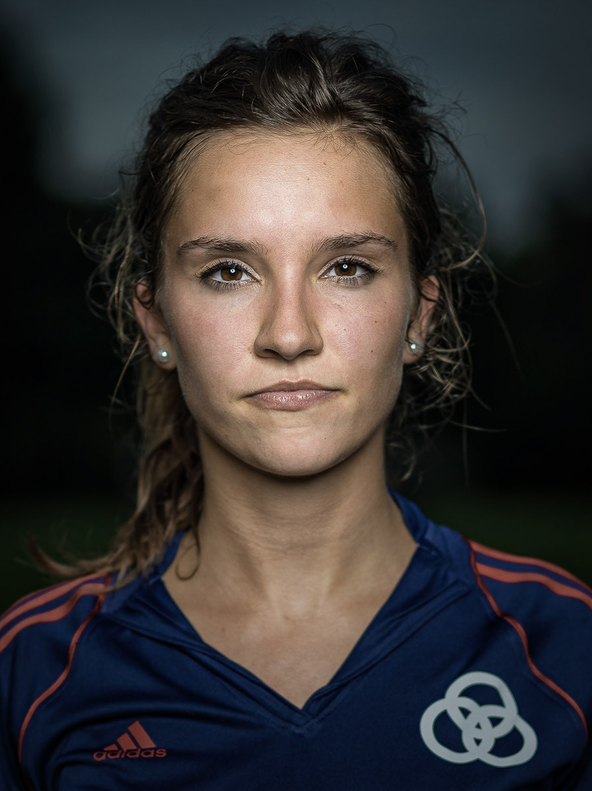 Starkes Porträt einer Sportlerin vor dunklen Hintergrund.