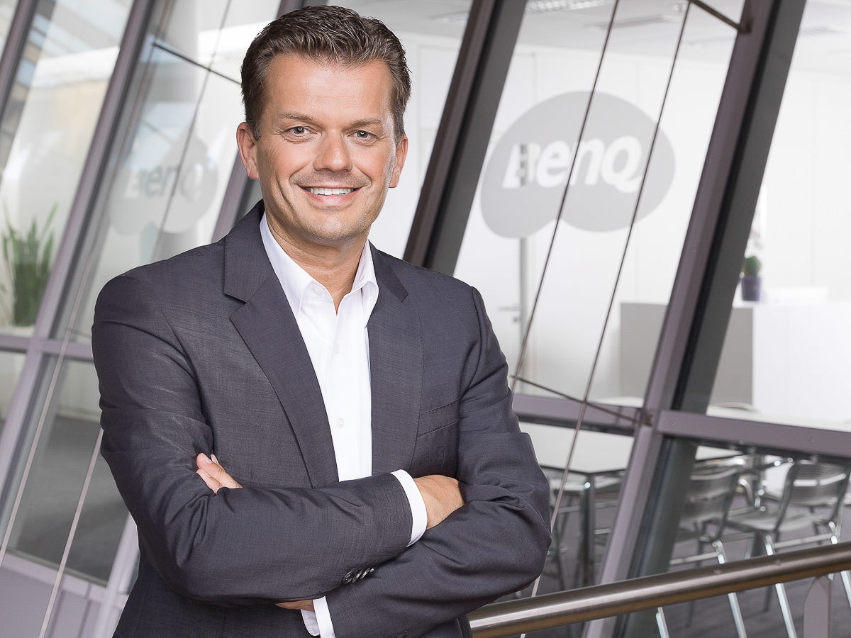 Portrait von einem Mann vor Logo des Kunden.
